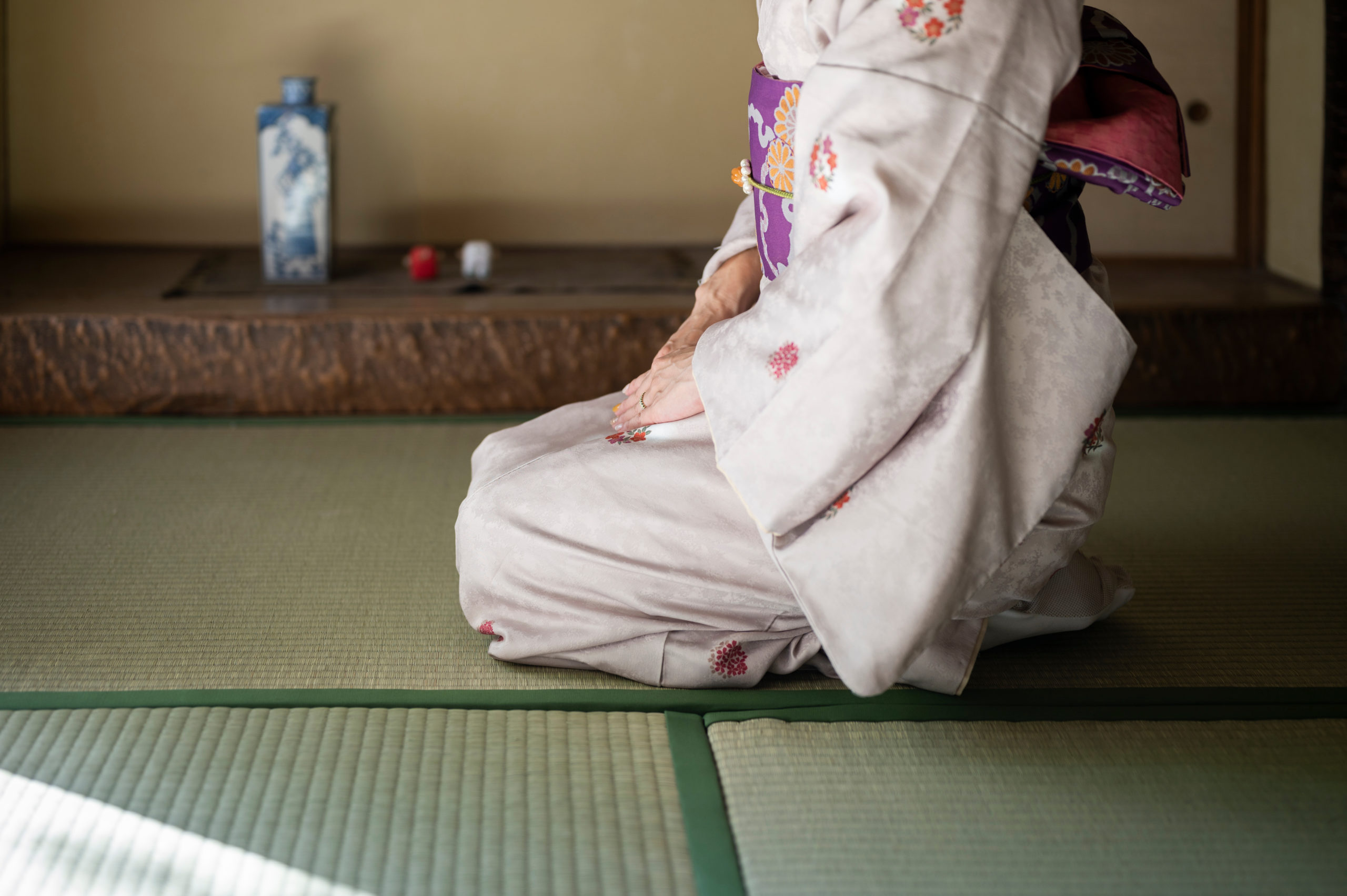 和室に正座して丁寧にお辞儀をする着物姿の女性